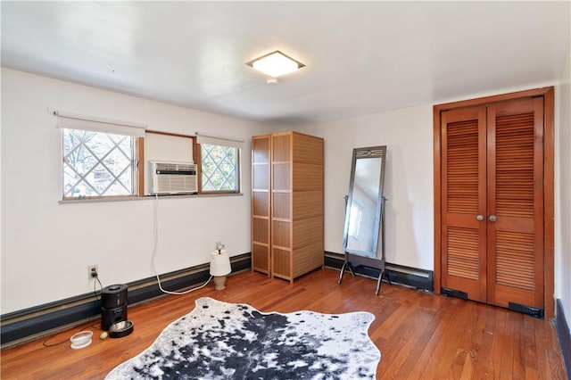 bedroom featuring a closet, cooling unit, wood-type flooring, and a baseboard radiator