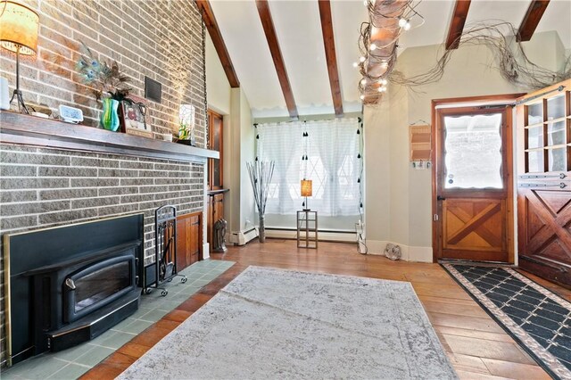 entryway with light wood-type flooring, baseboard heating, beam ceiling, high vaulted ceiling, and a wood stove