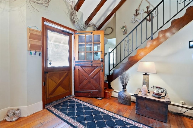 foyer entrance featuring baseboard heating, lofted ceiling with beams, and hardwood / wood-style flooring