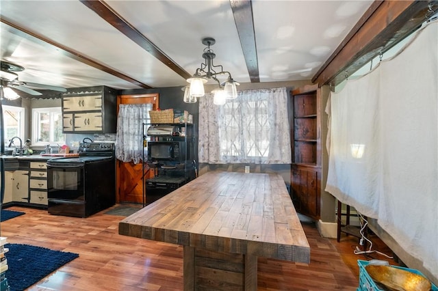 kitchen with beam ceiling, sink, black appliances, ceiling fan with notable chandelier, and hardwood / wood-style flooring