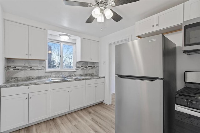 kitchen featuring backsplash, sink, light wood-type flooring, white cabinetry, and stainless steel appliances