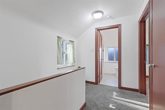 corridor with light carpet and vaulted ceiling