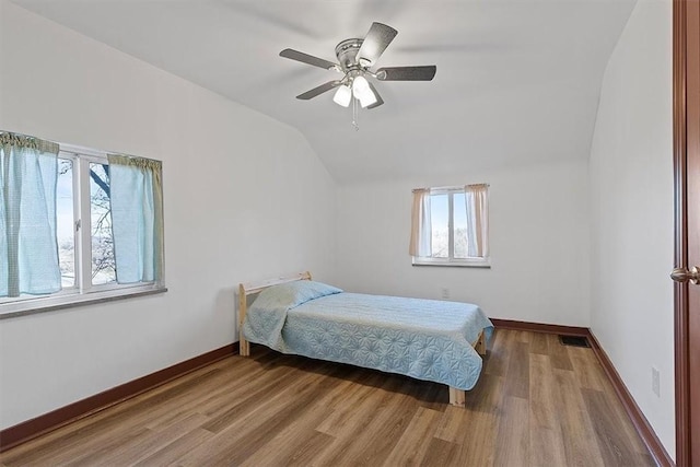 bedroom with ceiling fan, vaulted ceiling, and hardwood / wood-style flooring