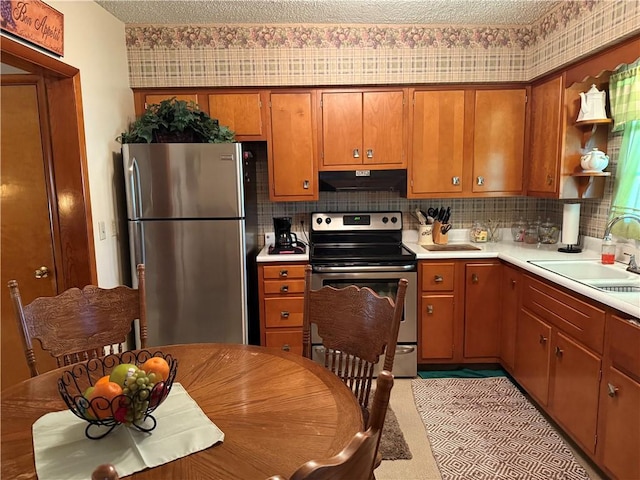 kitchen with decorative backsplash, a textured ceiling, stainless steel appliances, and sink