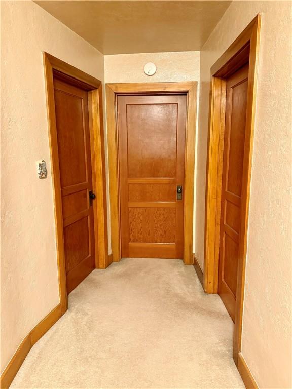 hall with light colored carpet