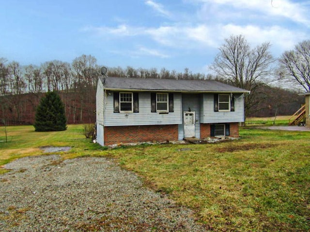 raised ranch featuring brick siding and a front yard