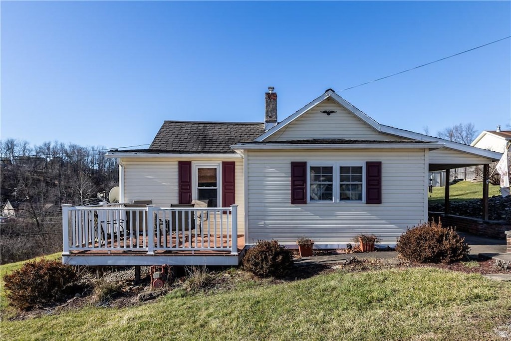 view of front of house featuring a front lawn, a deck, and a carport