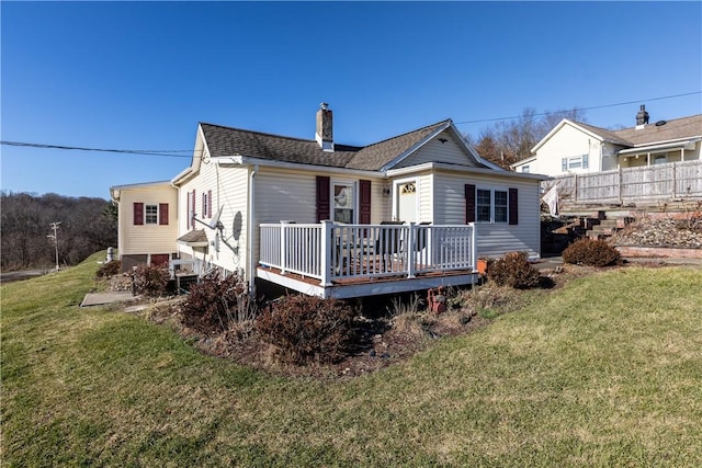 rear view of house featuring a wooden deck and a yard