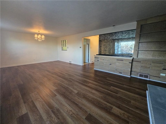 unfurnished living room with an inviting chandelier and dark wood-type flooring