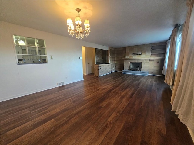 unfurnished living room featuring an inviting chandelier and dark wood-type flooring