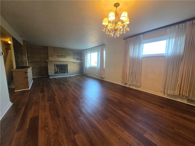 unfurnished living room featuring a chandelier, a large fireplace, and dark wood-type flooring