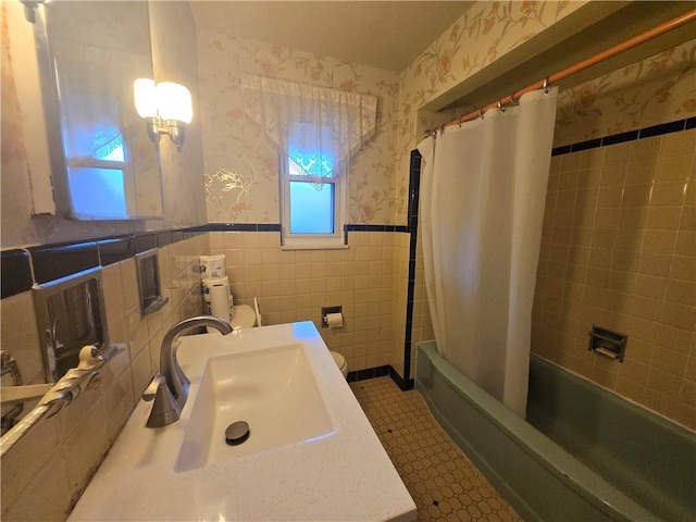 full bathroom with shower / bath combination with curtain, toilet, tile walls, and sink