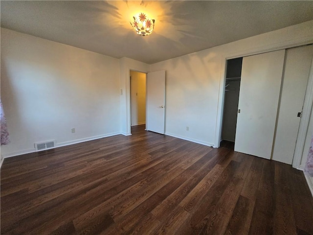 unfurnished bedroom featuring a closet and dark wood-type flooring