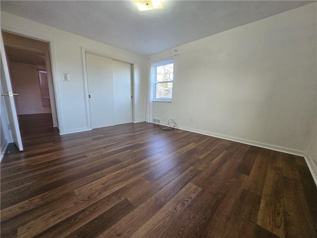 unfurnished bedroom with dark hardwood / wood-style floors and a closet