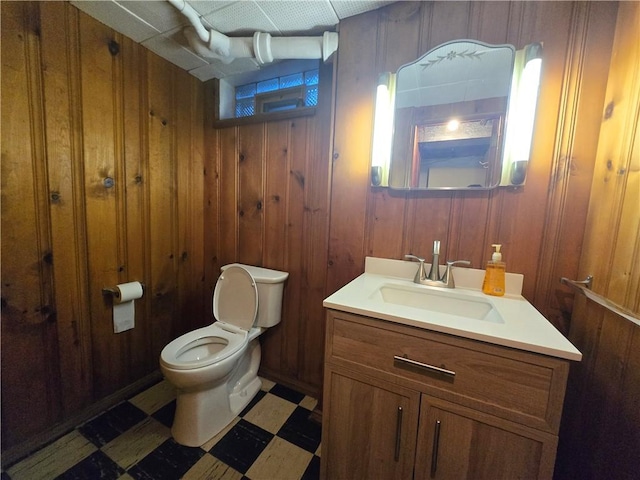 bathroom featuring wood walls, vanity, and toilet