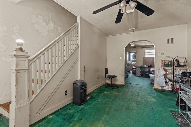 interior space with ceiling fan, dark carpet, and a textured ceiling