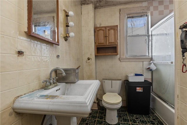 full bathroom with sink, enclosed tub / shower combo, tile walls, and toilet