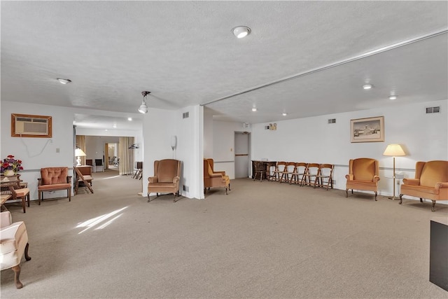 interior space featuring a textured ceiling, a wall mounted air conditioner, and light carpet