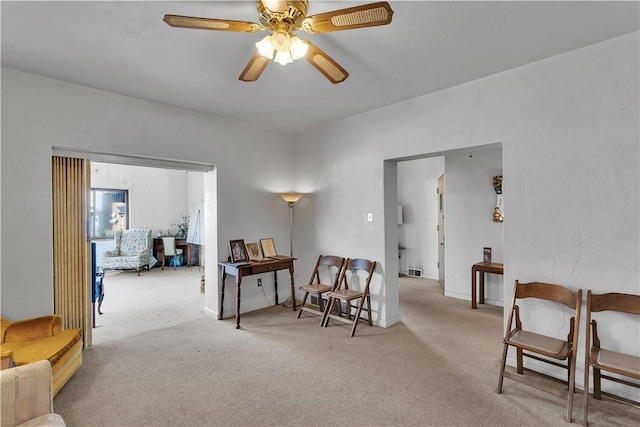 sitting room with ceiling fan and light colored carpet