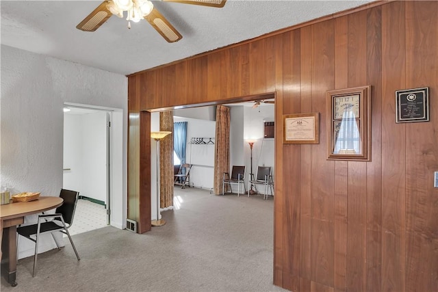 corridor with carpet flooring, plenty of natural light, and wooden walls