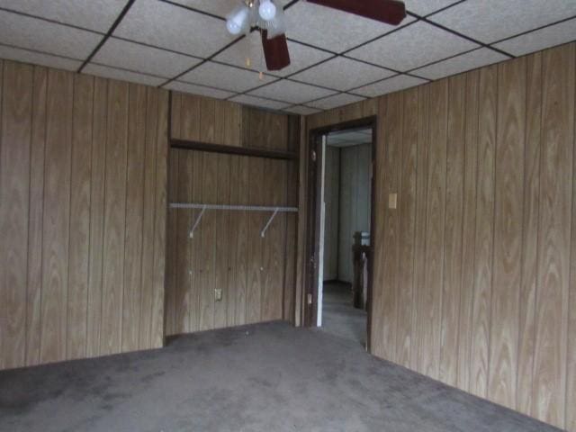 spare room featuring carpet, a paneled ceiling, and wooden walls