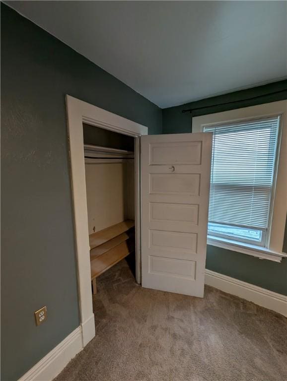 unfurnished bedroom featuring light colored carpet and a closet