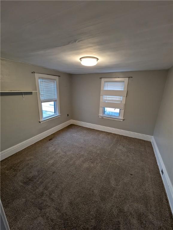 spare room with dark colored carpet