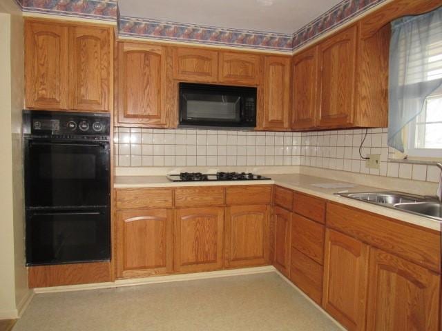 kitchen with decorative backsplash, sink, and black appliances