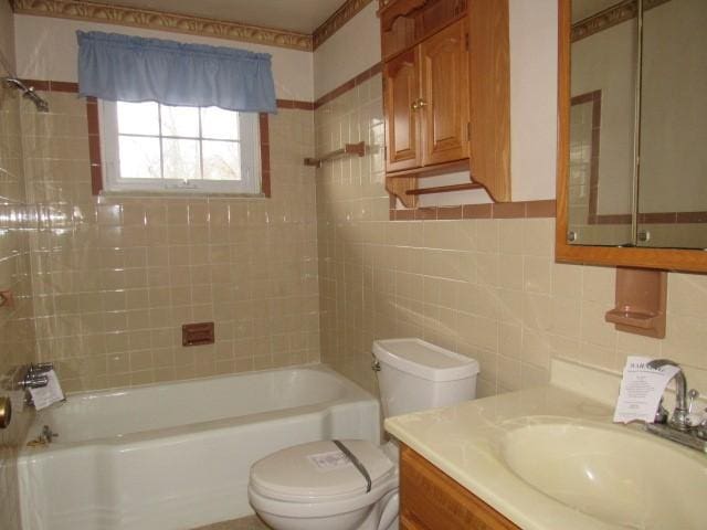 full bathroom featuring vanity, toilet, tile walls, and tiled shower / bath