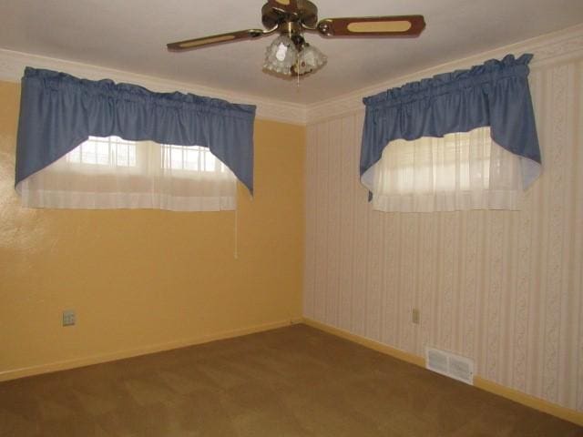 spare room featuring dark colored carpet, ceiling fan, and ornamental molding