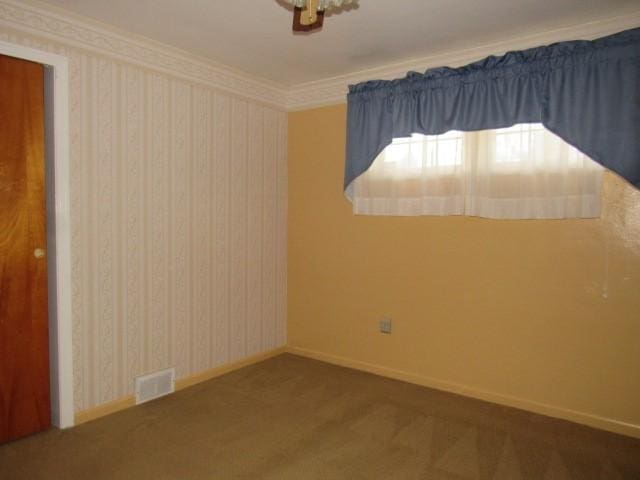 carpeted spare room featuring crown molding