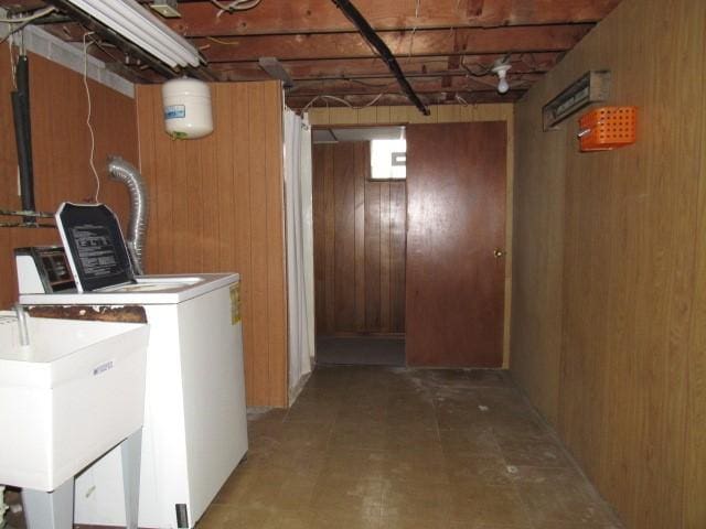 washroom with separate washer and dryer, sink, and wooden walls