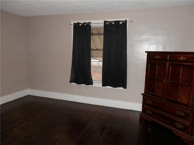 empty room featuring a textured ceiling and dark wood-type flooring