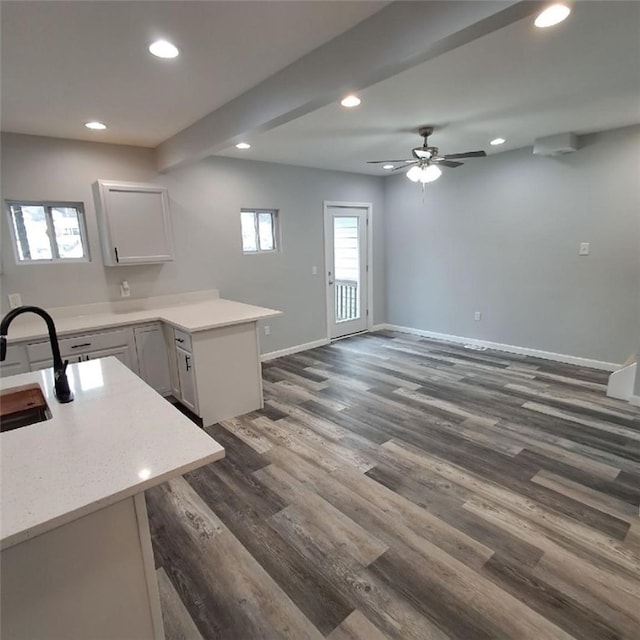 kitchen with kitchen peninsula, dark hardwood / wood-style flooring, ceiling fan, sink, and a center island