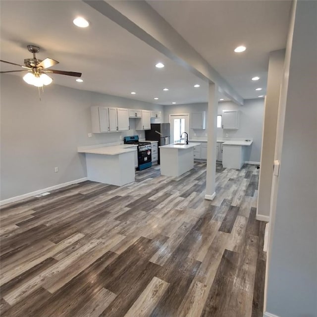 kitchen featuring black range, kitchen peninsula, dark hardwood / wood-style floors, ceiling fan, and white cabinetry