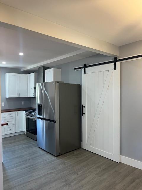 kitchen featuring appliances with stainless steel finishes, a barn door, dark hardwood / wood-style floors, and white cabinetry