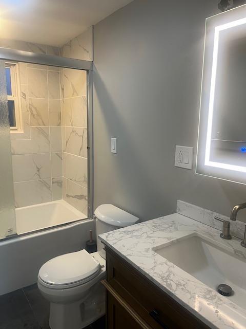 full bathroom featuring tile patterned flooring, vanity, toilet, and tiled shower / bath combo