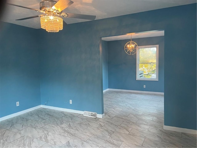 spare room featuring ceiling fan with notable chandelier