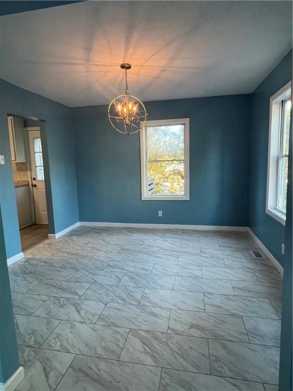 unfurnished room with an inviting chandelier and a healthy amount of sunlight