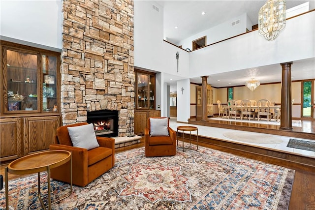 living room with a fireplace, a high ceiling, hardwood / wood-style flooring, and ornate columns