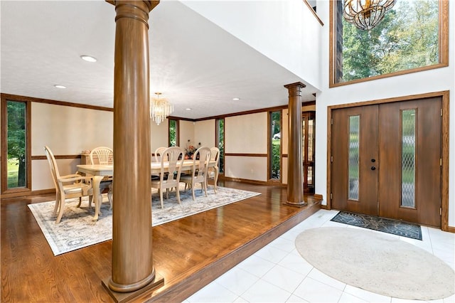 foyer entrance with a notable chandelier, light hardwood / wood-style floors, and ornate columns