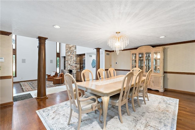 dining area with a textured ceiling, dark hardwood / wood-style flooring, and ornate columns