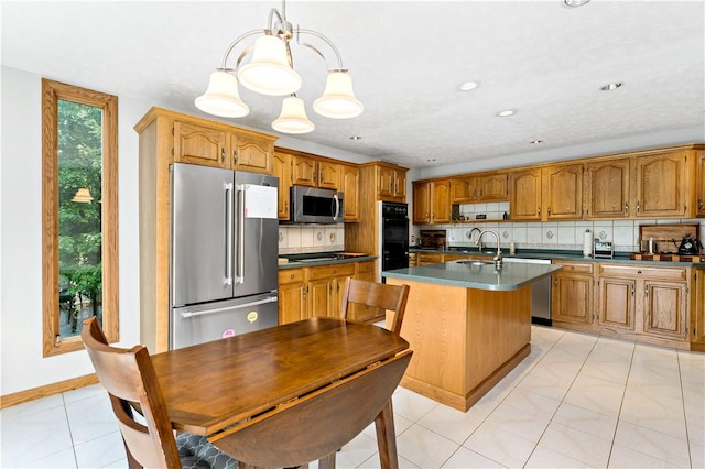 kitchen with decorative backsplash, light tile patterned floors, stainless steel appliances, and a kitchen island with sink