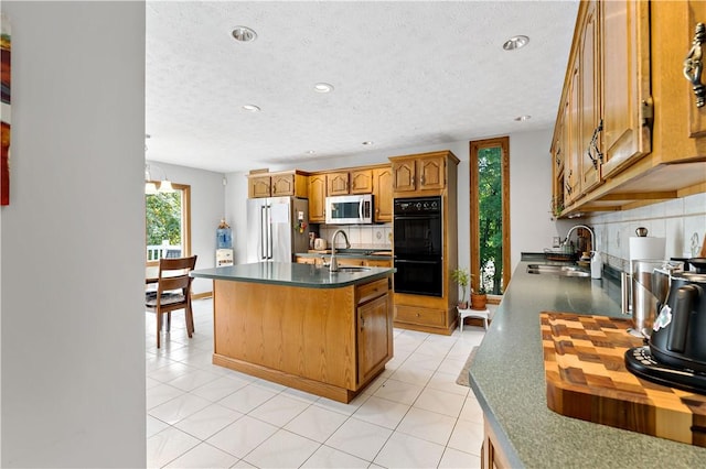 kitchen with decorative backsplash, sink, stainless steel appliances, and an island with sink