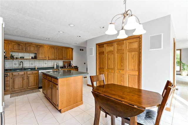 kitchen featuring decorative backsplash, sink, a center island with sink, a chandelier, and hanging light fixtures