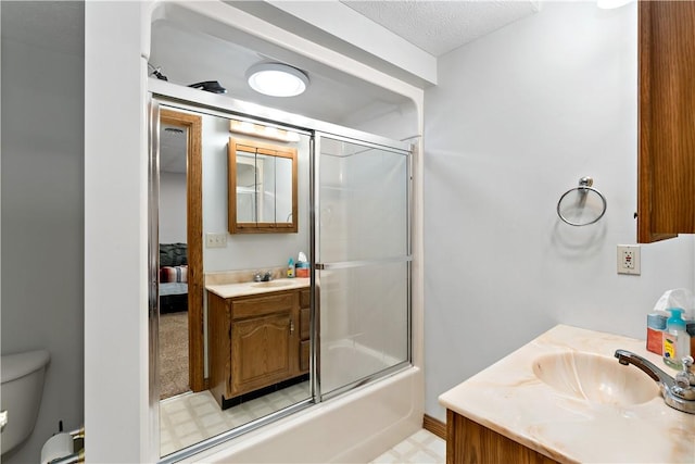 full bathroom featuring a textured ceiling, vanity, toilet, and bath / shower combo with glass door