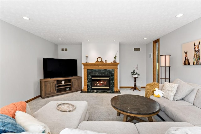 carpeted living room with a textured ceiling and a premium fireplace