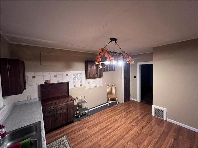 kitchen featuring an inviting chandelier, sink, hanging light fixtures, dark brown cabinetry, and wood-type flooring