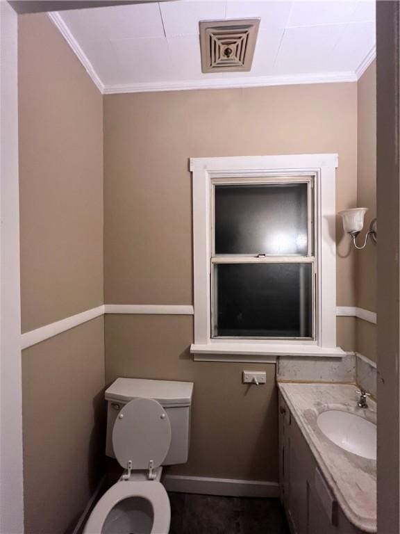 bathroom featuring toilet, ornamental molding, and sink