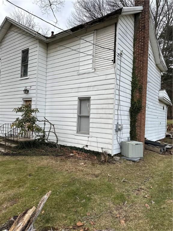 view of side of home with central AC and a lawn